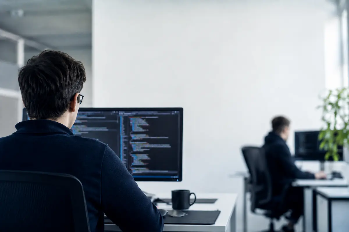 Desarrollador trabajando en código de espaldas en oficina